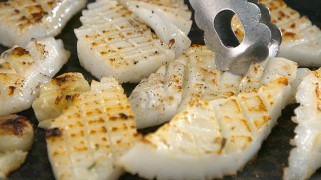 Squid being grilled until golden brown in a pan