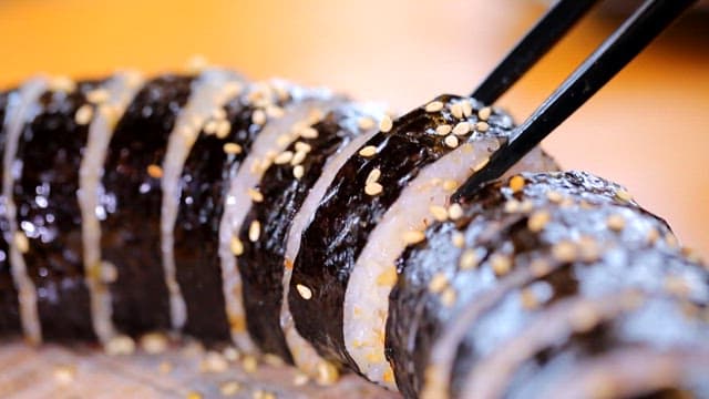 Chopstickful of spicy dombe gimbap sprinkled with sesame seeds