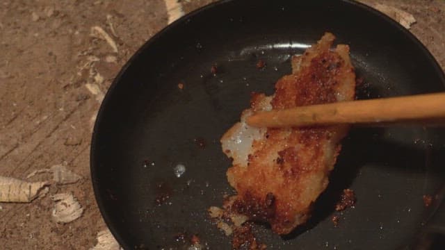 Chopsticks holding a piece of crispy fry