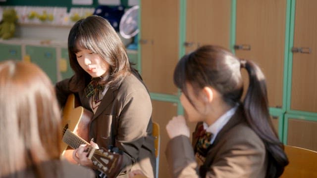 Student playing guitar in a classroom