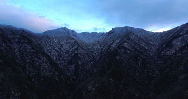Snow-covered mountains under cloudy skies
