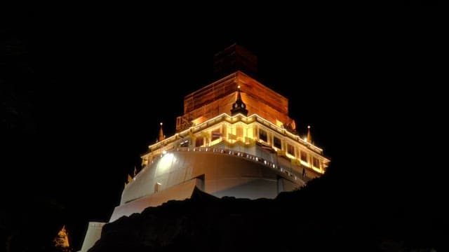 Looking up at the Thai temple brightly lit at night