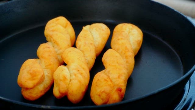 Delicious twisted doughnuts being cooked in a pan