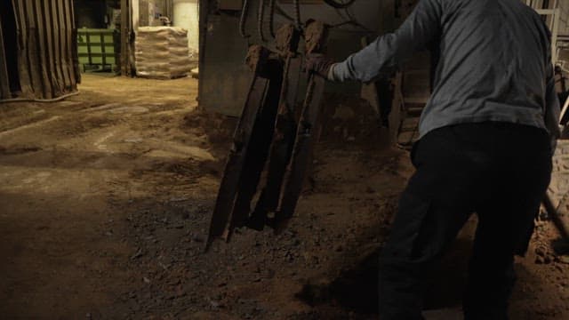 Worker handling manhole covers in a factory