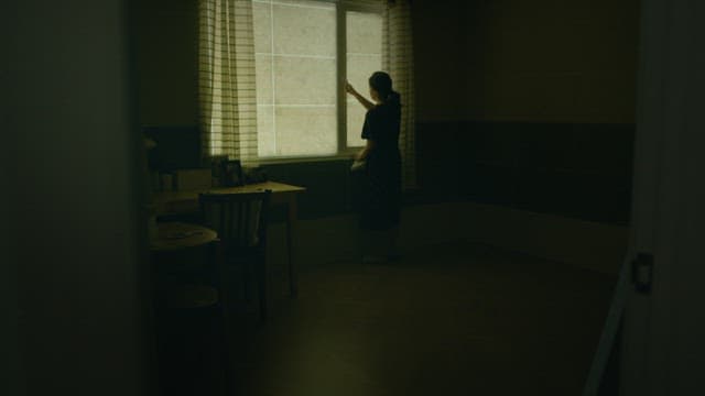 Woman opening window in a dim room