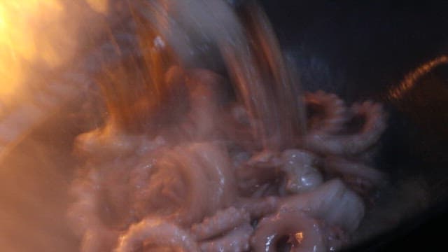 Stir-fried octopus with spicy sauce prepared in a restaurant kitchen