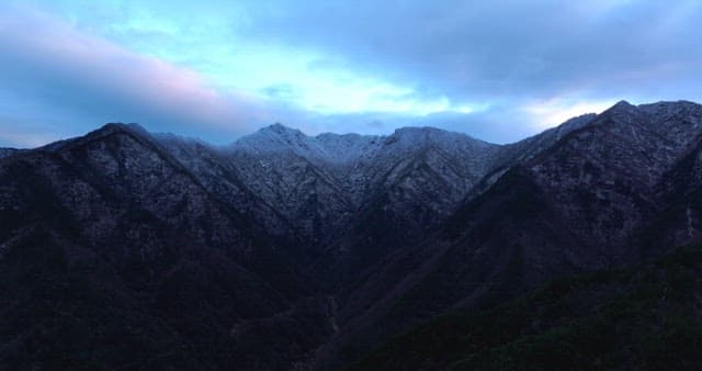 Snow-covered mountains under cloudy skies