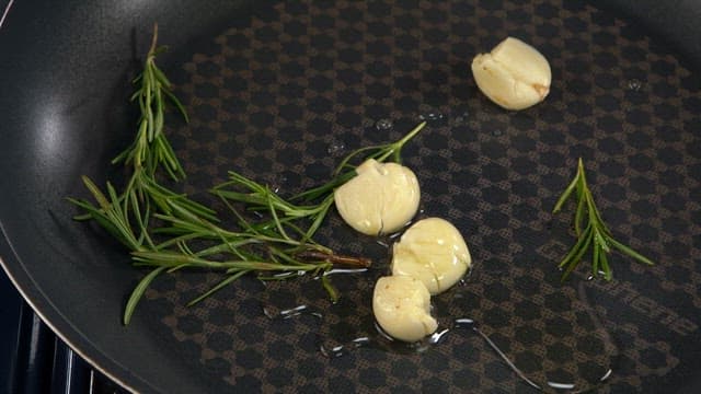 Squid being grilled with garlic and rosemary in a pan