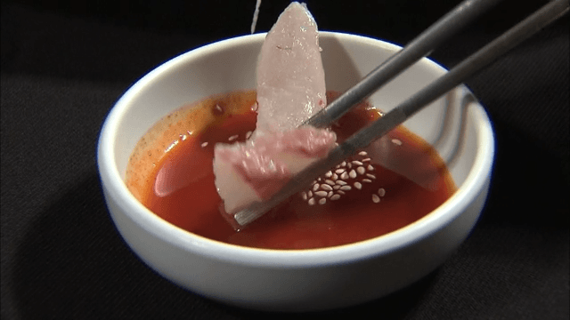 Slicing fresh sashimi dipped in red chili-pepper paste with vinegar