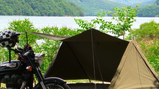 Motorcycle parked next to a tent near a lake