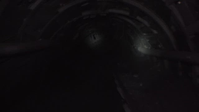 Inside a dark coal mine tunnel, illuminated by dim lights