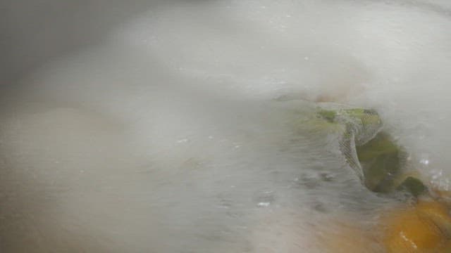 Steaming vegetables and broth in large pot in the kitchen