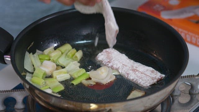 Frying green onions and hairtail in oil in a frying pan