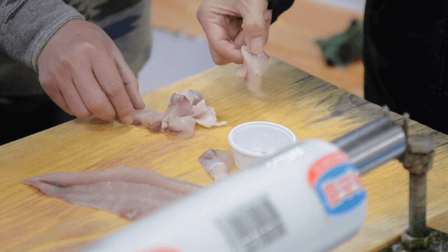 People Eating Freshly Prepared Raw Fish Dipped in Red Sauce