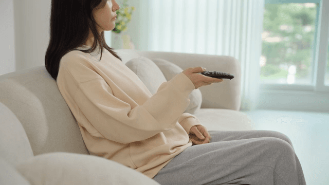 Woman operating a remote control on the sofa