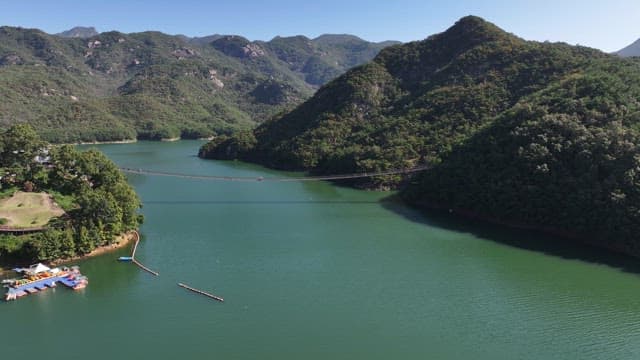 View of a Suspension Bridge with Scenic Lake and Mountain