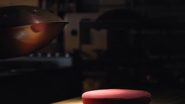 Person examining a handpan in a dimly lit room