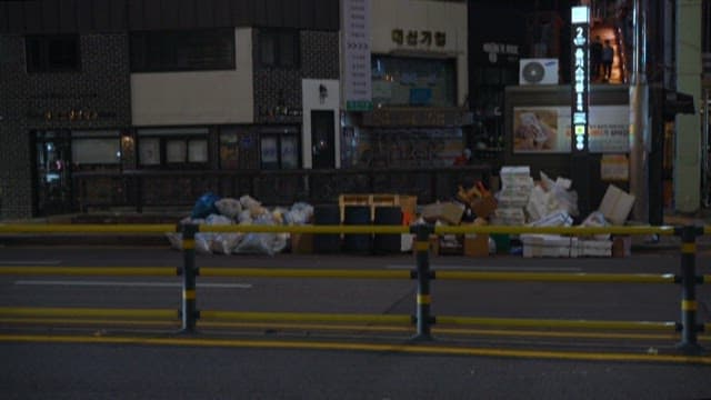 Empty urban street and garbage at night with passing cars