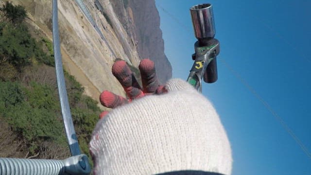 Worker tightening bolts that hold metal cables in place in the air