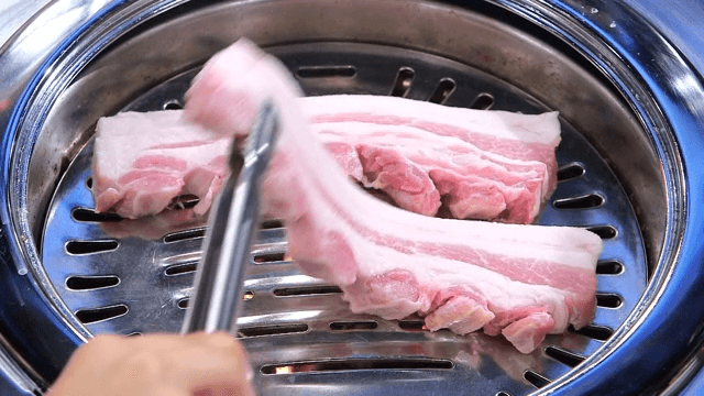 Raw pork belly on a metal grill