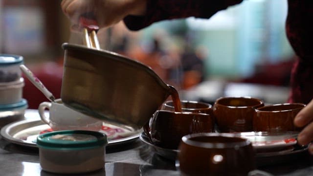 Pouring Tea into Cups at a Table