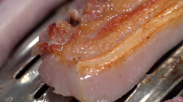 Grilled pork belly sizzling on a grill