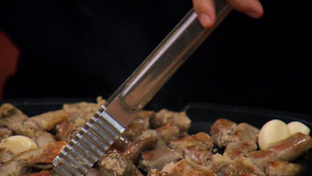 Cutting instetine with tongs and scissors on a hot iron plate