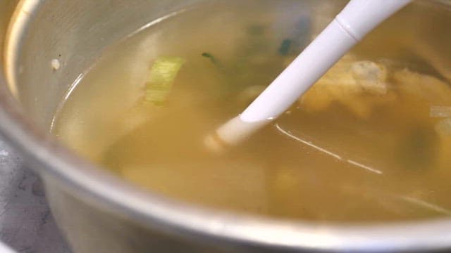 Hands testing soybean paste soup salinity with a salinity meter indoors