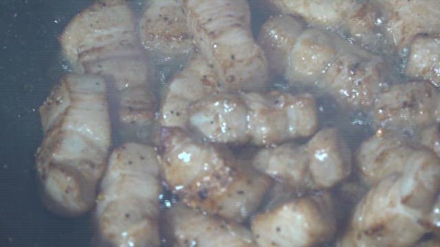Pork belly sizzling in a frying pan