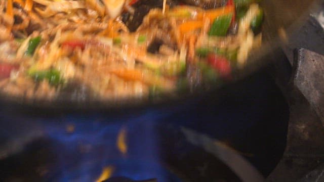Stir-frying vegetables and meat in a hot wok