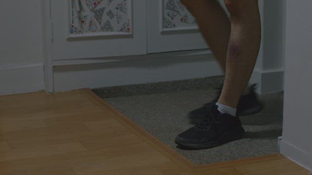 People's feet taking off their shoes at the front door before entering the house