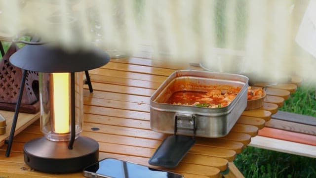 Outdoor picnic table setting with spicy ramen and kimchi