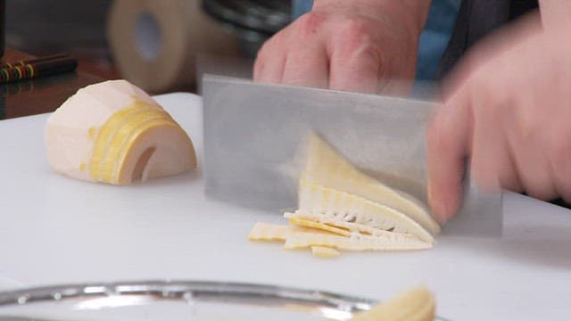 Cutting boiled bamboo shoots with a knife on a cutting board