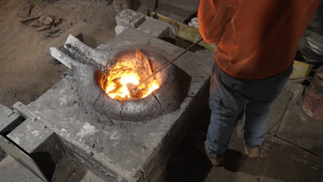 Worker handling molten metal in a foundry