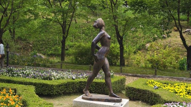 Bronze Statue Among Flower Beds in Park