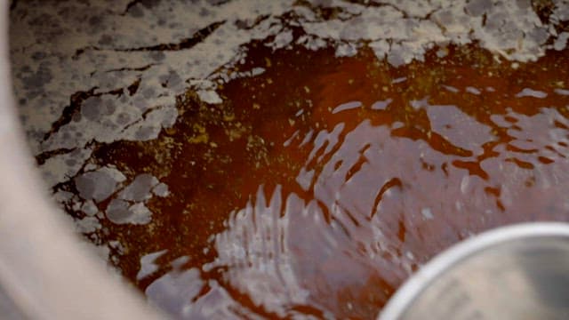 Using a ladle to scoop up soy sauce from a crock