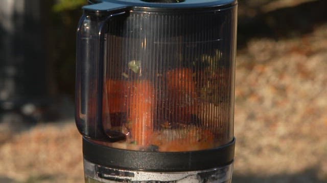 Making juice outdoors by blending fresh vegetables in a blender