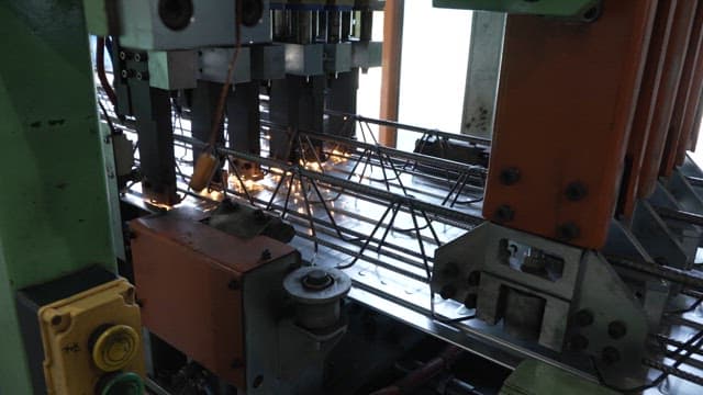 Machine welding metal rods in a factory