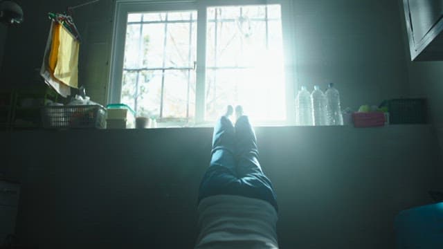 Man doing push-ups in a dimly lit room with sunlight streaming through the window