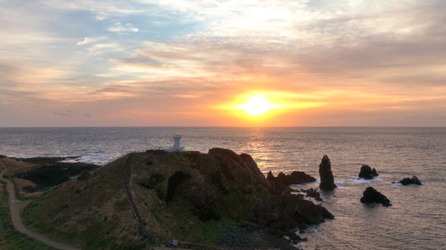Sunset over a coastal landscape with a lighthouse