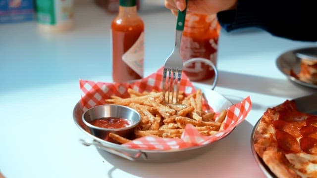 Fries and pizza with ketchup on a table