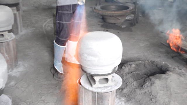 Heating the surface of a cast iron cauldron with a torch in a workshop