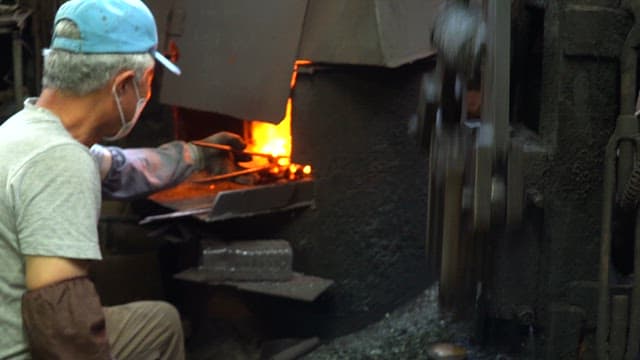 Worker forging metal in a factory