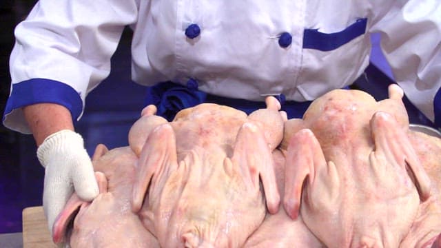 Chef preparing raw chickens on a tray