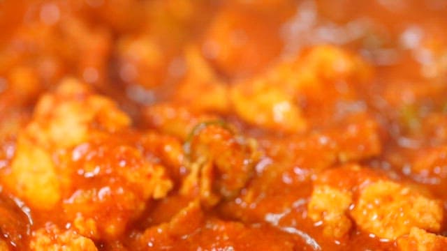 Spoonful of spicy pork stew with tofu simmering