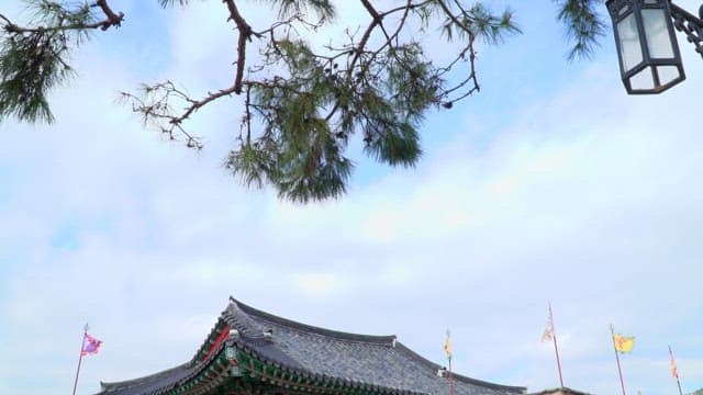 Entrance to an ancient Korean walled town with flags under a blue sky
