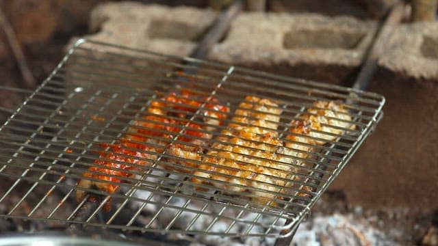 Applying sauce to eel grilled over charcoal