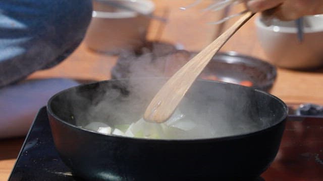 Putting webfoot octopus in a frying pan with vegetables