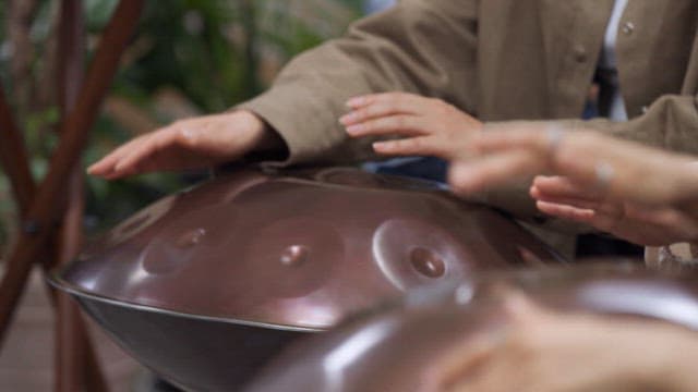 Multiple people playing handpan instruments