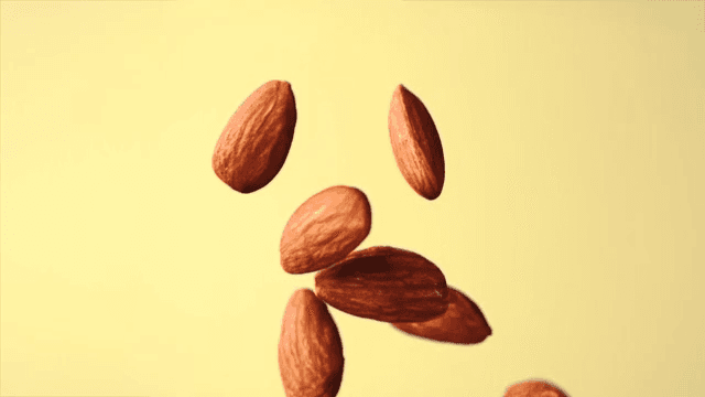Almonds falling in slow motion against a yellow background